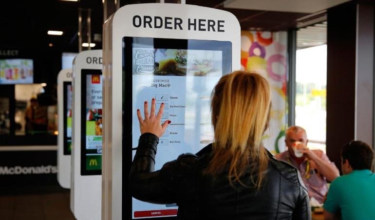 Cliente utilizando un kiosco autoservicio para ordenar en el restaurante
